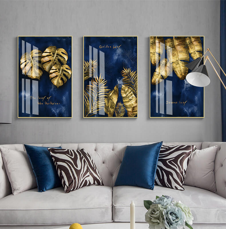 Set di tre quadri “Foglie Dorate”: foglie dorate su sfondo blu intenso, composizione elegante e armoniosa.