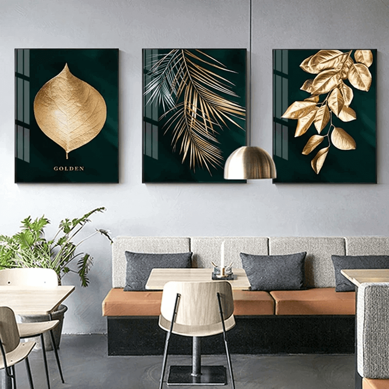 Set di 3 quadri “Speranza Gold” appeso in soggiorno moderno, foglie dorate su sfondo verde intenso