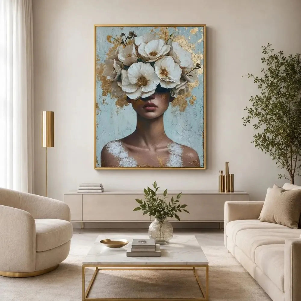 Anima in fiore quadro su tela con cornice oro di una donna con il volto nascosto da un rigoglioso copricapo di fiori bianchi e dettagli in foglia oro su uno sfondo materico azzurro e bianco.