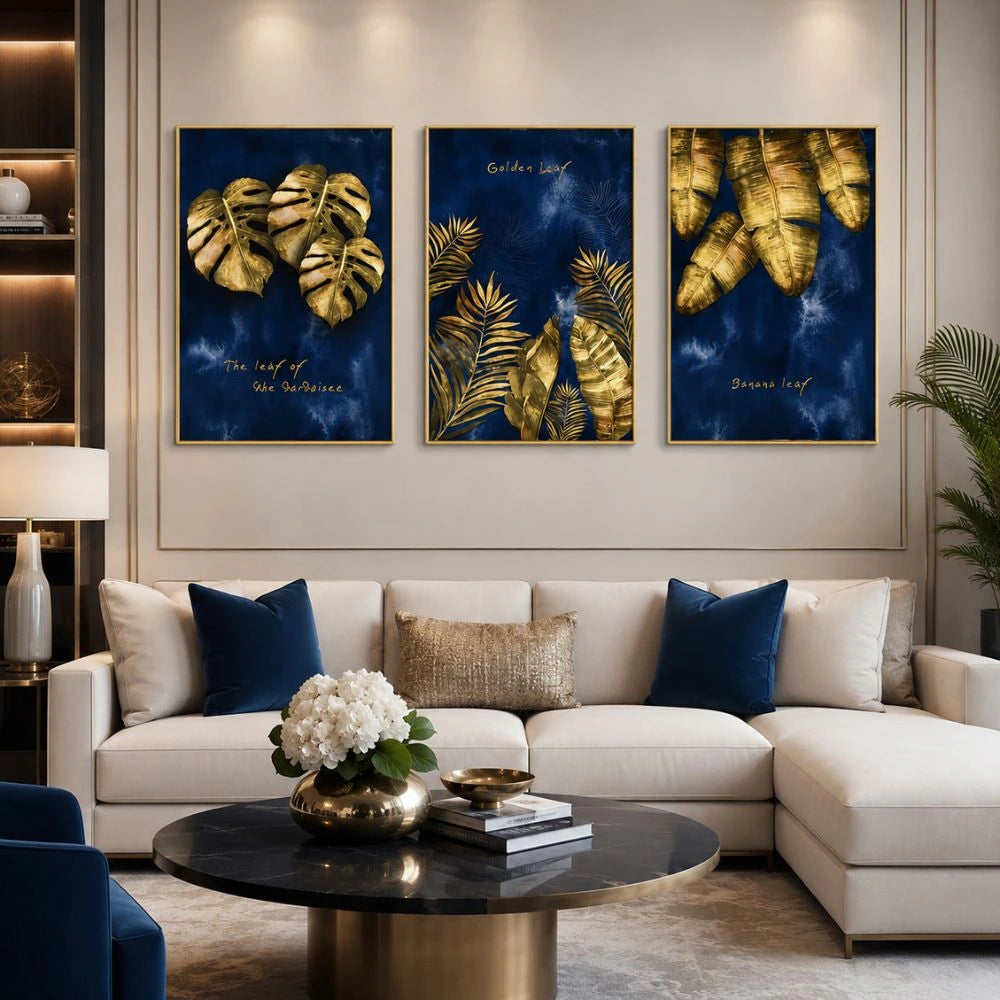 Set di tre quadri “Foglie Dorate”: foglie dorate su sfondo blu intenso, composizione elegante e armoniosa.